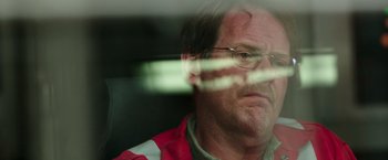 Movie still from “Deepwater Horizon” (2016), directed by Peter Berg – A person wearing glasses and a red and white jacket; Close Up shot, Over the shoulder angle