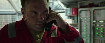 Movie still from “Deepwater Horizon” (2016), directed by Peter Berg – A man in a red jacket talking on a phone; Close Up shot, Low angle