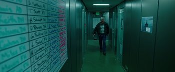 Movie still from “Deepwater Horizon” (2016), directed by Peter Berg – A man walking down a hallway in a building; Wide shot, High angle