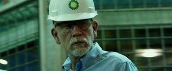 Movie still from “Deepwater Horizon” (2016), directed by Peter Berg – An older man wearing a hard hat and glasses; Close Up shot, Over the shoulder angle