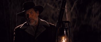 Movie still from “Django Unchained” (2012), directed by Quentin Tarantino – A man in a hat and a coat standing next to a lantern; Medium shot, Low angle