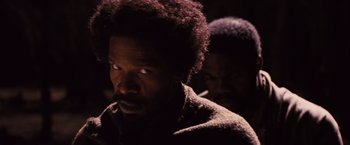 Movie still from “Django Unchained” (2012), directed by Quentin Tarantino – A man in a dark room with his eyes wide open; Close Up shot, Over the shoulder angle