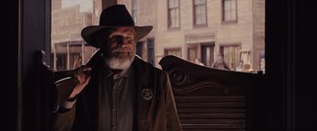 Movie still from “Django Unchained” (2012), directed by Quentin Tarantino – An old man with a beard wearing a cowboy hat; Medium shot, Over the shoulder angle