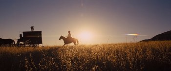 Movie still from “Django Unchained” (2012), directed by Quentin Tarantino – A man riding a horse through a field at sunset; Extreme Wide shot, Low angle