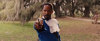 Movie still from “Django Unchained” (2012), directed by Quentin Tarantino – A man holding a gun pointed at the camera; Close Up shot, Over the shoulder angle