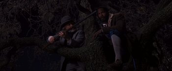 Movie still from “Django Unchained” (2012), directed by Quentin Tarantino – Two men in a tree with a gun in their hands; Medium shot, High angle