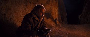 Movie still from “Django Unchained” (2012), directed by Quentin Tarantino – A man sitting in a cave holding a tray of food; Medium shot, Over the shoulder angle