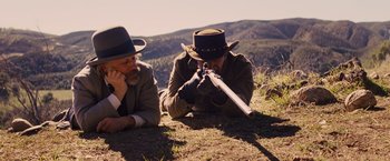 Movie still from “Django Unchained” (2012), directed by Quentin Tarantino – Two men laying on the ground looking at a rifle; Medium shot, High angle