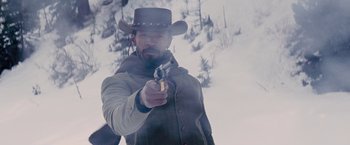 Movie still from “Django Unchained” (2012), directed by Quentin Tarantino – A man in a cowboy hat holding a gun in the snow; Medium shot, Low angle