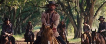 Movie still from “Django Unchained” (2012), directed by Quentin Tarantino – A man sitting on top of a brown horse; Medium shot, Low angle