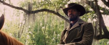 Movie still from “Django Unchained” (2012), directed by Quentin Tarantino – A man wearing a cowboy hat in front of a tree; Medium shot, Low angle