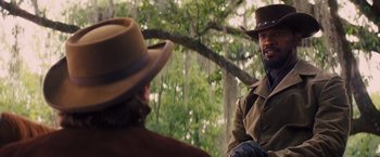Movie still from “Django Unchained” (2012), directed by Quentin Tarantino – A man in a brown jacket and a man in a brown cowboy hat; Medium shot, Over the shoulder angle