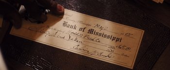 Movie still from “Django Unchained” (2012), directed by Quentin Tarantino – A hand is holding a bank of mississippis check; Extreme Close Up shot, High angle