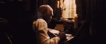 Movie still from “Django Unchained” (2012), directed by Quentin Tarantino – An older man writing on a book at a desk; Medium shot, High angle
