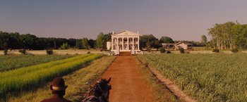 Movie still from “Django Unchained” (2012), directed by Quentin Tarantino – A horse and carriage traveling down a dirt road near a large building; Extreme Wide shot, Low angle