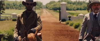 Movie still from “Django Unchained” (2012), directed by Quentin Tarantino – A man riding a horse down a dirt road; Medium shot, Over the shoulder angle