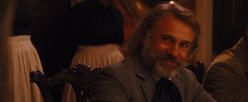 Movie still from “Django Unchained” (2012), directed by Quentin Tarantino – A man with a long beard sitting in front of a woman; Close Up shot, Over the shoulder angle