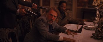 Movie still from “Django Unchained” (2012), directed by Quentin Tarantino – A man sitting at a table in front of a camera; Medium shot, Over the shoulder angle