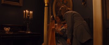 Movie still from “Django Unchained” (2012), directed by Quentin Tarantino – Two people standing in front of a harp and a painting; Medium shot, Over the shoulder angle