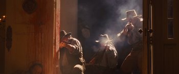 Movie still from “Django Unchained” (2012), directed by Quentin Tarantino – A group of men with guns in a room with smoke coming out of them; Medium shot, Low angle