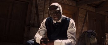 Movie still from “Django Unchained” (2012), directed by Quentin Tarantino – A man in a vest and tie sitting in a room; Close Up shot, High angle