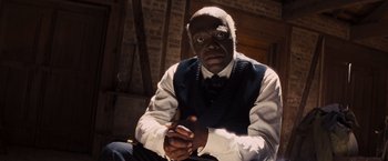 Movie still from “Django Unchained” (2012), directed by Quentin Tarantino – A man in a vest and tie sitting in a room; Close Up shot, Low angle