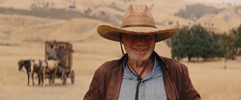 Movie still from “Django Unchained” (2012), directed by Quentin Tarantino – An older man wearing a cowboy hat in the middle of the desert; Close Up shot, Over the shoulder angle