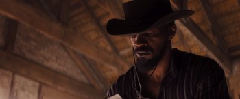 Movie still from “Django Unchained” (2012), directed by Quentin Tarantino – A man in a cowboy hat looking down at a book; Close Up shot, Low angle