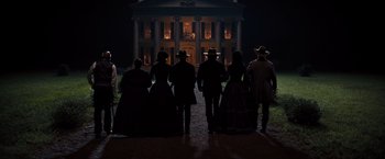 Movie still from “Django Unchained” (2012), directed by Quentin Tarantino – A group of people standing in front of a building at night; Wide shot, Low angle