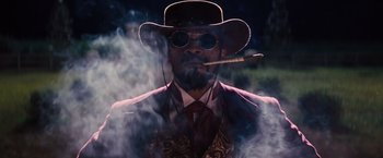 Movie still from “Django Unchained” (2012), directed by Quentin Tarantino – A man in a hat smoking a cigar and wearing sunglasses; Medium shot, Low angle