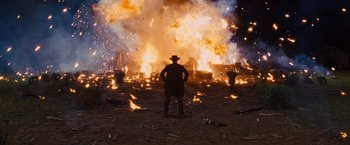 Movie still from “Django Unchained” (2012), directed by Quentin Tarantino – A man standing in front of a fire with his hands on his hips; Wide shot, Low angle