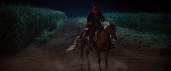 Movie still from “Django Unchained” (2012), directed by Quentin Tarantino – A man riding a horse down a dirt road at night; Wide shot, Low angle