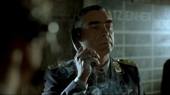 Movie still from “Downfall” (2004), directed by Oliver Hirschbiegel – An older man in a military uniform talking on a phone; Close Up shot, Low angle
