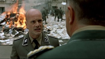 Movie still from “Downfall” (2004), directed by Oliver Hirschbiegel – A man in a military uniform talking to another man in fatigues; Close Up shot, Over the shoulder angle