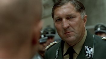 Movie still from “Downfall” (2004), directed by Oliver Hirschbiegel – A man in a military uniform looking at another man; Close Up shot, Low angle