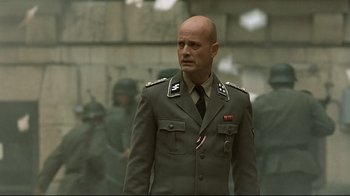 Movie still from “Downfall” (2004), directed by Oliver Hirschbiegel – A man in a military uniform standing in front of a group of soldiers; Medium shot, Low angle