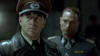 Movie still from “Downfall” (2004), directed by Oliver Hirschbiegel – A man in a military uniform stands next to another man in a military uniform; Close Up shot, Over the shoulder angle
