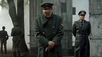 Movie still from “Downfall” (2004), directed by Oliver Hirschbiegel – A man in a military uniform standing next to another man in a uniform; Medium shot, Low angle