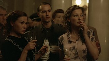 Movie still from “Downfall” (2004), directed by Oliver Hirschbiegel – A group of men and women standing next to each other holding wine glasses; Medium shot, Over the shoulder angle
