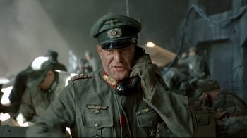Movie still from “Downfall” (2004), directed by Oliver Hirschbiegel – A man in a military uniform talking on a phone; Medium shot, Low angle