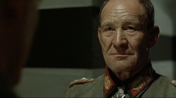 Movie still from “Downfall” (2004), directed by Oliver Hirschbiegel – An older man wearing a military uniform and a medal around his neck; Close Up shot, Over the shoulder angle