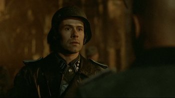 Movie still from “Downfall” (2004), directed by Oliver Hirschbiegel – A man wearing a helmet and a leather jacket; Close Up shot, Over the shoulder angle