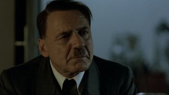 Movie still from “Downfall” (2004), directed by Oliver Hirschbiegel – An older man in a suit and tie looking sad; Close Up shot, Over the shoulder angle