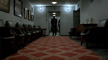 Movie still from “Downfall” (2004), directed by Oliver Hirschbiegel – A man is standing in a hallway with chairs; Wide shot, High angle