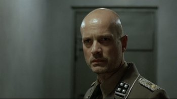 Movie still from “Downfall” (2004), directed by Oliver Hirschbiegel – A man with a bald head wearing a military uniform; Close Up shot, Low angle