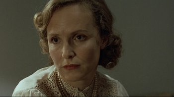 Movie still from “Downfall” (2004), directed by Oliver Hirschbiegel – An older woman wearing a white shirt and a gold necklace; Close Up shot, Over the shoulder angle