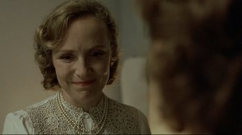 Movie still from “Downfall” (2004), directed by Oliver Hirschbiegel – A person wearing a necklace near a mirror; Close Up shot, Over the shoulder angle