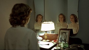 Movie still from “Downfall” (2004), directed by Oliver Hirschbiegel – A woman looking in the mirror with a picture of a man; Medium shot, Over the shoulder angle