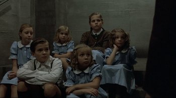 Movie still from “Downfall” (2004), directed by Oliver Hirschbiegel – A group of children sitting next to each other in a room; Medium shot, High angle