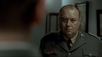 Movie still from “Downfall” (2004), directed by Oliver Hirschbiegel – A man in a military uniform looking at the camera; Close Up shot, Over the shoulder angle